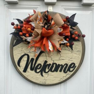 This burlap and berries fall door hanger measures 18" in diameter and is 1" thick. It is stained front and back, features a crackle paint technique and a laser cut "welcome". It's finished off with a handmade bow of five ribbons and some fall berries. Made by Bead and Board in our small shop in Iowa. Truly a one of a kind find!
