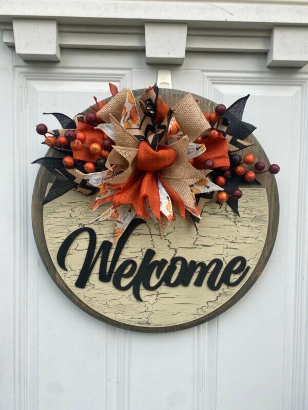 This burlap and berries fall door hanger measures 18" in diameter and is 1" thick. It is stained front and back, features a crackle paint technique and a laser cut "welcome". It's finished off with a handmade bow of five ribbons and some fall berries. Made by Bead and Board in our small shop in Iowa. Truly a one of a kind find!